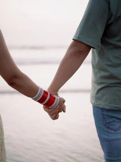 A simple gesture of holding hands speaks volumes. This shot focuses on their connection as they walk towards the sea, symbolizing the start of their new journey together.