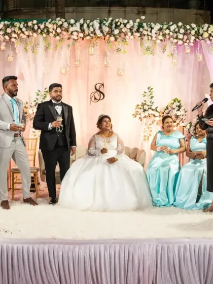 The wedding party on stage during the speeches. This photo captures a formal part of the reception, showing the couple with their bridesmaids and groomsmen.
