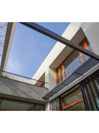 A low-angle view of the RT Nagar Residence, showing the clean lines of the white structure against the sky. The design uses simple forms and a restrained color palette to create a sense of modern, minimalist elegance.