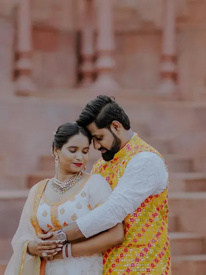 A close-up embrace that feels warm and intimate. The focus is entirely on the couple's connection, with the architectural background adding a sense of place.