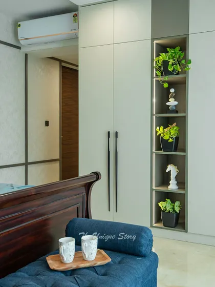 This image shows the custom wardrobe unit, which includes an open, lit shelving niche for displaying decor and plants. This design breaks the monotony of the wardrobe and adds a personal touch.