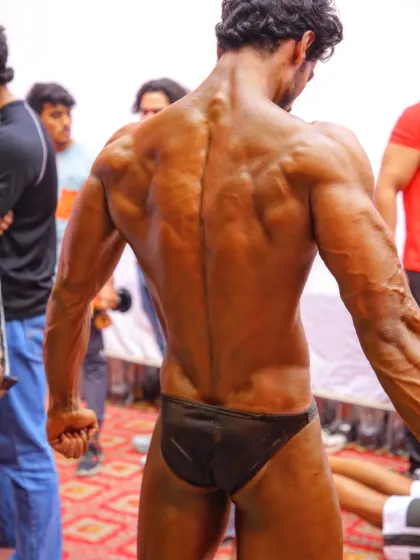 The 'demon back' pose, captured right before stepping on stage. A strong, detailed back is a sign of true hard work and a staple of a championship physique.