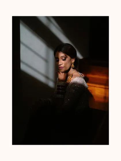 A bride sits in shadow, with stripes of light illuminating her face. This artistic, high-contrast portrait is both dramatic and deeply soulful.