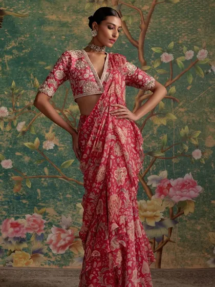 A beautiful red printed and draped saree, styled against a floral backdrop. This look is both romantic and modern.