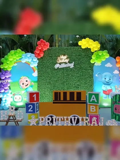 This outdoor Cocomelon party setup features a grass wall backdrop and colorful balloon arrangements, perfect for a garden celebration.