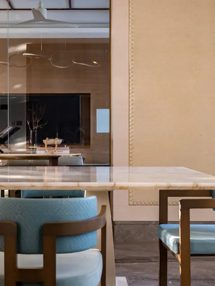 A closer look at the dining area, where the reflection in the mirror shows the open connection to the living space. The blue woven leather chairs add a lively pop of color against the neutral tones.