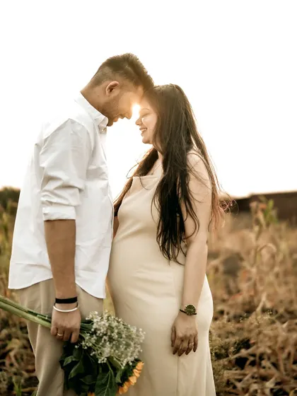 A stunning golden hour portrait. The couple touches foreheads as the sun flares behind them, creating a magical and romantic silhouette.