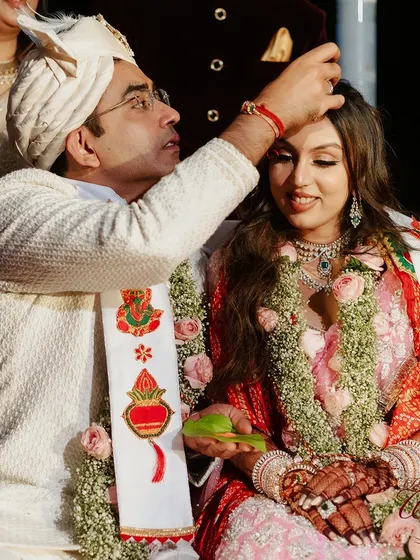 The groom applying 'sindoor' to the bride's forehead, a key ritual signifying their marital status.