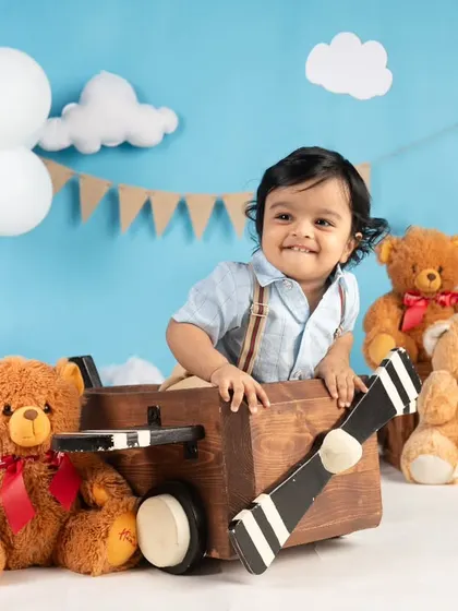 This little pilot is all smiles in his wooden airplane, surrounded by his teddy bear co-pilots. A creative and fun theme for a first birthday.