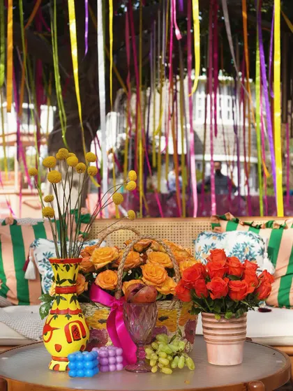 A playful detail from the garden Mehendi, with colorful ribbons hanging from a tree and bright, quirky vases on the table.