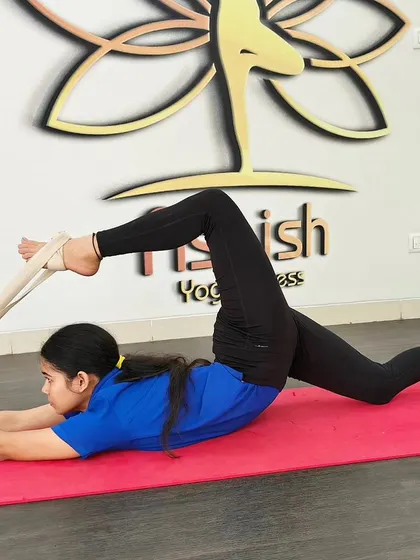 A yoga strap is used to gently pull the leg into a deeper stretch in this reclining leg pose.