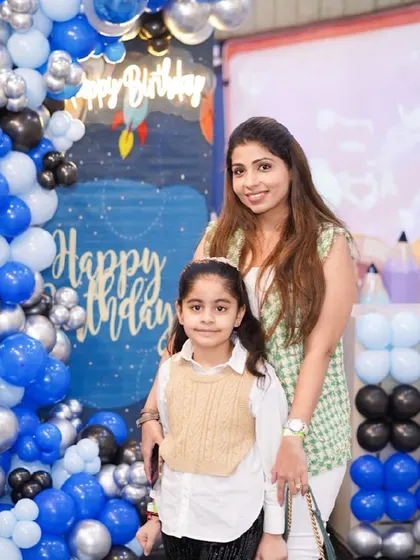 A mother and daughter share a sweet moment, posing for a photo at a space-themed party.