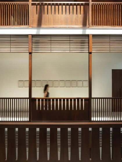 The blur of a person walking along an upper corridor highlights the dynamic nature of the central atrium. This core of the home is a space of constant, gentle movement and connection.