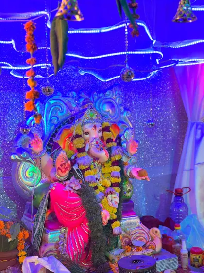 Another close-up of the Ganpati idol, showing the details of the blue lighting, the shimmering backdrop, and the hanging decorative elements.