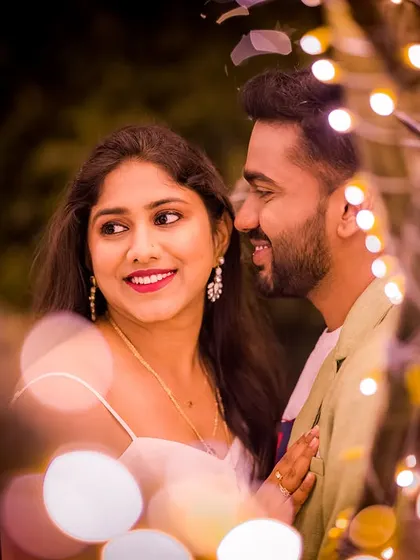 A happy, candid moment captured through a frame of glowing lights. This shot highlights the couple's joy and the magical atmosphere of the night shoot.