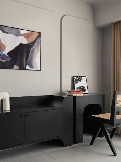 This bedroom has a retro 80s feel, with a custom-designed black bed and a matching TV and study unit. The black Chandigarh chair and abstract art complete the moody, sophisticated look.