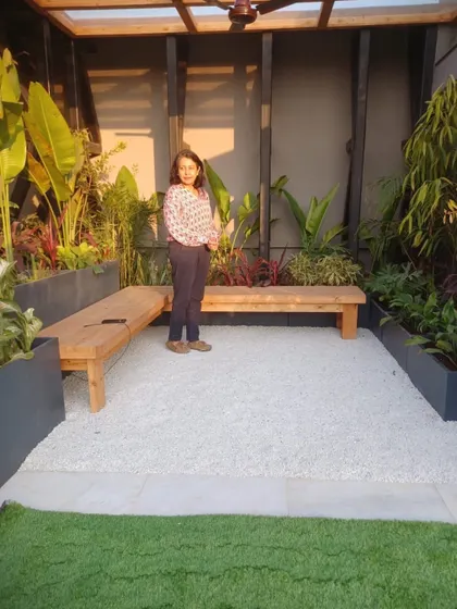 A rooftop garden in Delhi, pictured in January right after installation. With enough sun, plants can survive severe winters. This space features a gravel seating area flanked by planters and wooden benches.