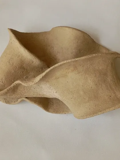 A delicate, flowing sculpture made from a single slab of clay. The beauty is in its simplicity and the gentle folds that create a sense of movement.