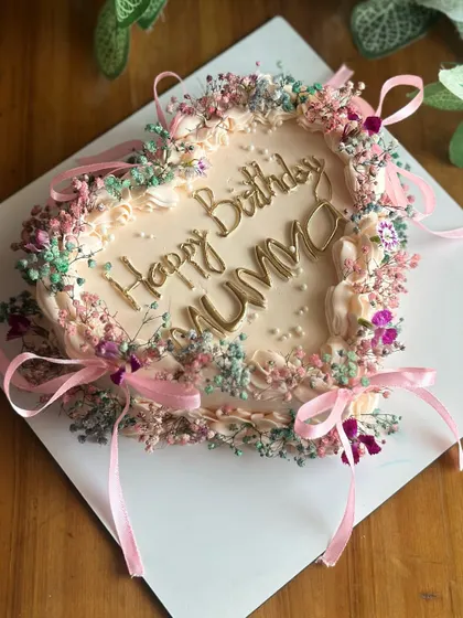 A cake straight out of a vintage dream. This heart-shaped creation is delicately adorned with baby's breath and tiny ribbons, perfect for a romantic and elegant birthday.