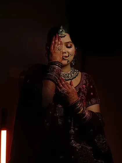 An artistic, low-light photo that creates a sense of mystery and elegance. The makeup is focused on a strong highlight and defined eyes, which are visible even in the shadows.