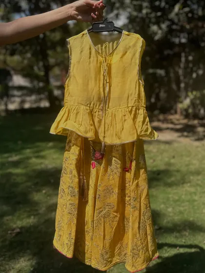 This yellow lehenga set features a peplum top with ruffles and a printed skirt with delicate tassels. This image shows the fine details that make my outfits unique and special.