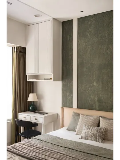 The young couple's bedroom uses a palette of olive green and white with sharp lines for a look of subtle elegance. A compact study desk is integrated next to the bed for functionality.