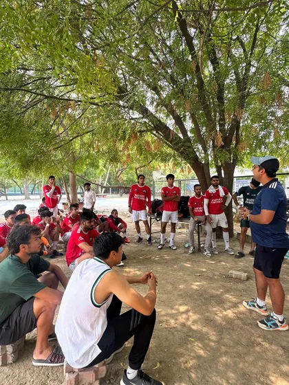 A team talk under the shade of a tree, showing how we adapt and strategize in any environment. This is grassroots football with a professional mindset.