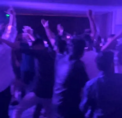 The ABB employees dancing with hands in the air under purple lighting.