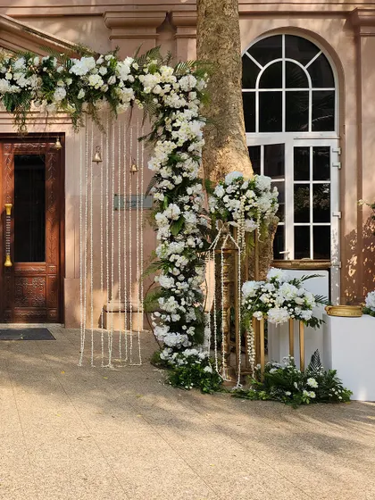 Another angle of the elegant white floral arch, perfectly framing the venue's classic wooden doors.