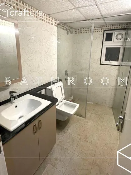 A simple and functional bathroom design with a vanity for storage and a glass partition for the shower area, keeping the space clean and dry.