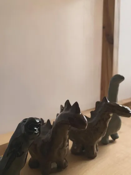 A herd of tiny dinosaurs, fresh from the kiln. These miniature sculptures are glazed in earthy, muted tones and are perfect for adding a touch of prehistoric fun to a shelf or desk.