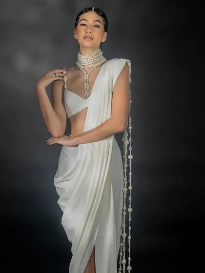 An elegant, posed shot for Nikhil Thampi, highlighting the graceful lines of the saree and the cascading pearl details.