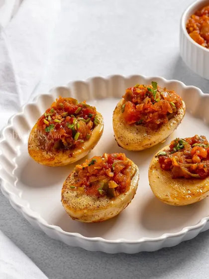 Small potato skins stuffed with a savory tomato filling, a perfect bite-sized appetizer.