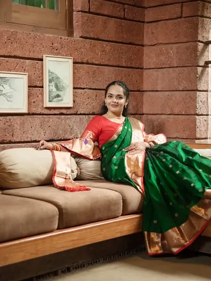 A full-length portrait of the bride looking confidently at the camera, showcasing the graceful drape of her saree and her radiant smile.