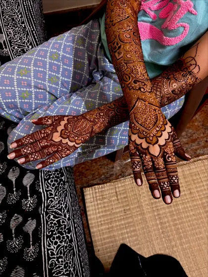 This full bridal design features a beautiful blend of traditional Indian and Arabic styles. The patterns are dense on the palms and fingers, with more open, flowing designs on the arms.
