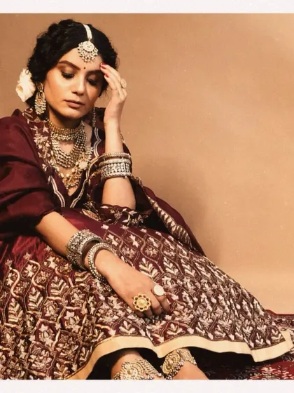 A full-length view of the bride's intricately embroidered lehenga. The deep maroon color and detailed craftsmanship are central to this heritage-inspired look we curated for her.