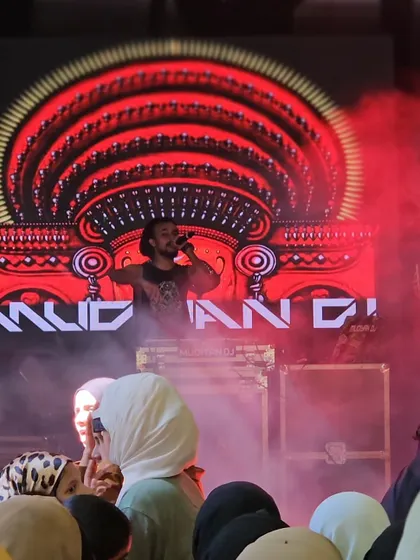 Performing in front of my custom Theyyam-inspired LED graphic, surrounded by red smoke. This visual is a core part of my brand identity.