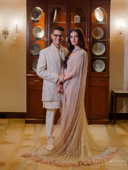 A full-length portrait showcasing the couple's stunning, coordinated outfits in an elegant, classic setting.