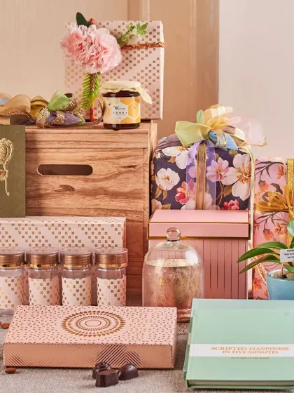 This pastel-themed festive arrangement shows a softer aesthetic, with floral gift boxes, a live orchid plant, gourmet jam, and other delicate treats packed into a stylish wooden crate.