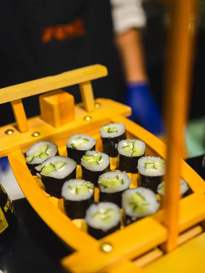 Freshly made cucumber maki rolls presented in a traditional wooden sushi boat.
