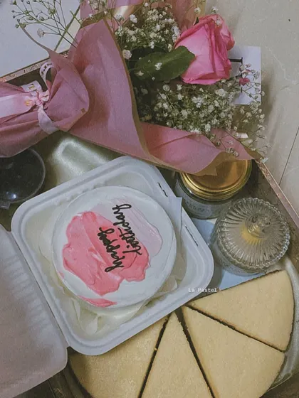 This pink-themed hamper includes a bento cake, a cheesecake, a scented candle, and a bouquet of flowers.