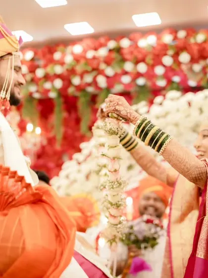 The garland exchange ceremony. The bride looks up at her groom, her makeup looking fresh and perfect for this iconic wedding moment.