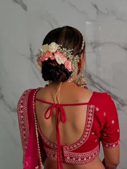 A detailed view of a classic bridal bun, intricately woven and adorned with fresh pink and white roses and baby's breath for a touch of romance.