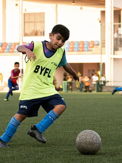 A player in a bib dribbles with determination, embodying our philosophy of wanting to be the best.