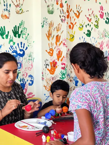 A mother and her children work together on painting a solar system model during a family workshop day.