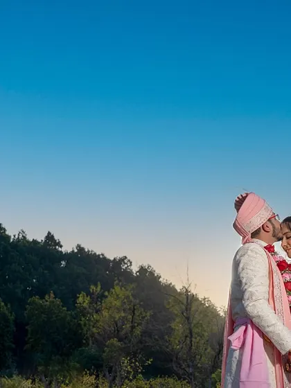 A tender forehead kiss against the backdrop of a setting sun and blue sky. A truly romantic and serene portrait.