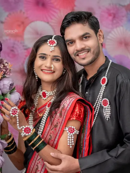 A smiling couple poses together in a floral setting for their Makarsankranti photoshoot. This portrait highlights the connection and happiness between the couple during the festive season.