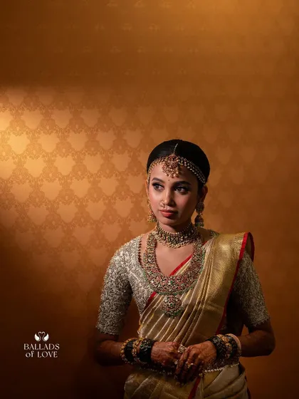 A beautifully lit portrait of a bride in her gold saree. The intricate details of her custom embroidered blouse are clearly visible, showcasing the quality of the craftsmanship.