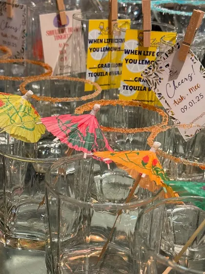 Fun and festive glasses ready for a party, garnished with colorful cocktail umbrellas and custom tags.