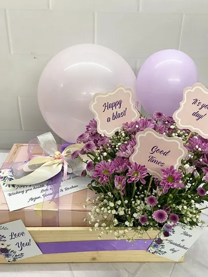 A sweet and celebratory hamper perfect for Mother's Day. The purple chrysanthemums are paired with pastel balloons and cute message cards for a fun and festive touch.
